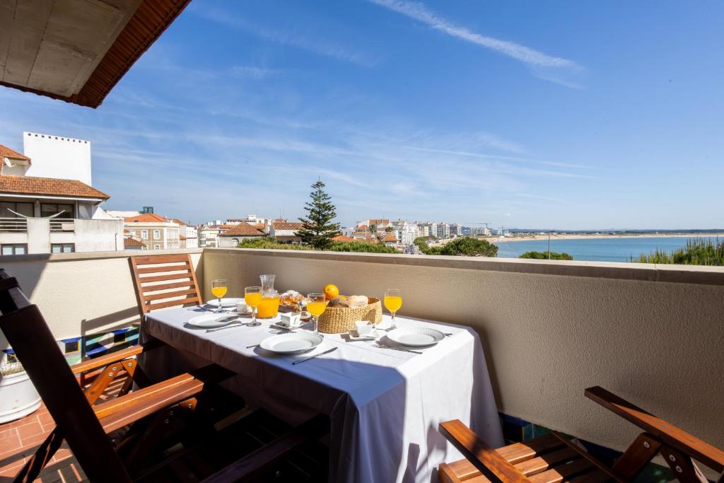 a table on a balcony with a view of the ocean at Caís in São Martinho do Porto