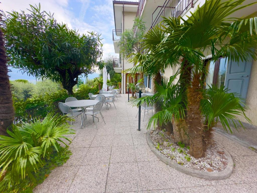 een binnenplaats met tafels en stoelen en palmbomen bij Hotel Silvana Garnì in Limone sul Garda