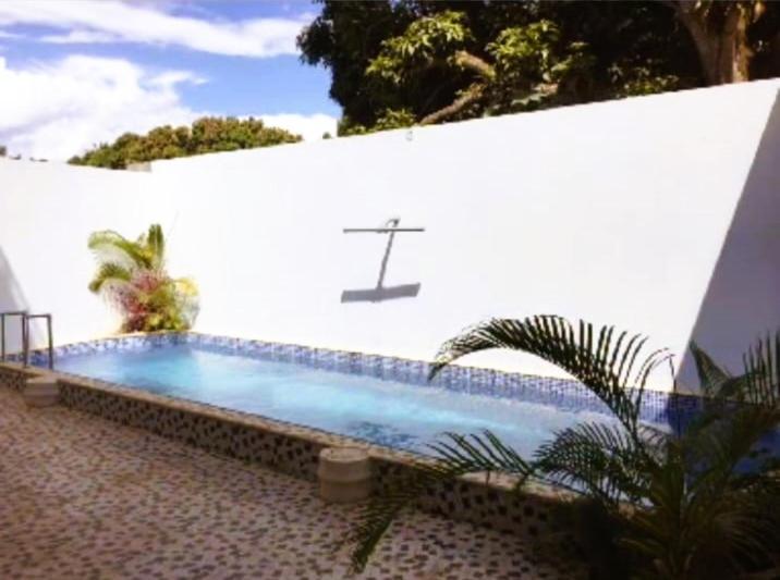 a swimming pool in front of a white wall at LA CASA DE ABI Y EMILIIO in Tarapoto