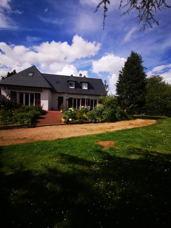 a house with a large yard with a green lawn at Les Logis de Catherine et Serge in Genêts