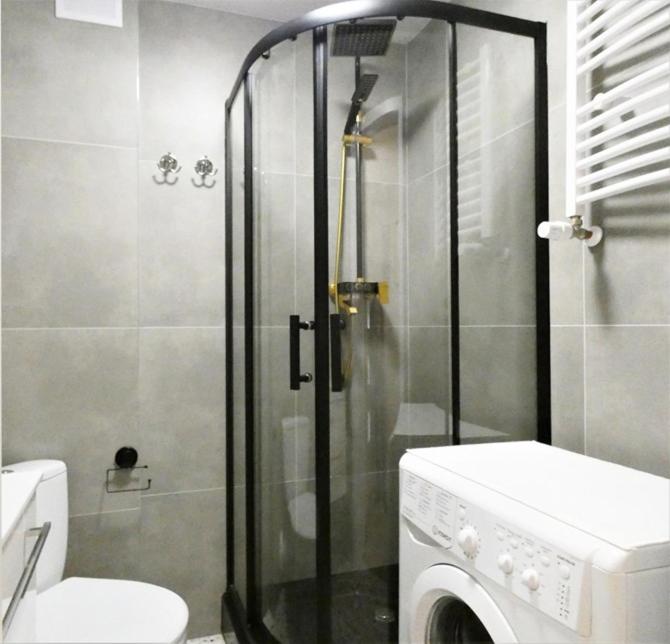 a bathroom with a shower and a washing machine at Hola Apartamenty Legionow 2 in Łódź