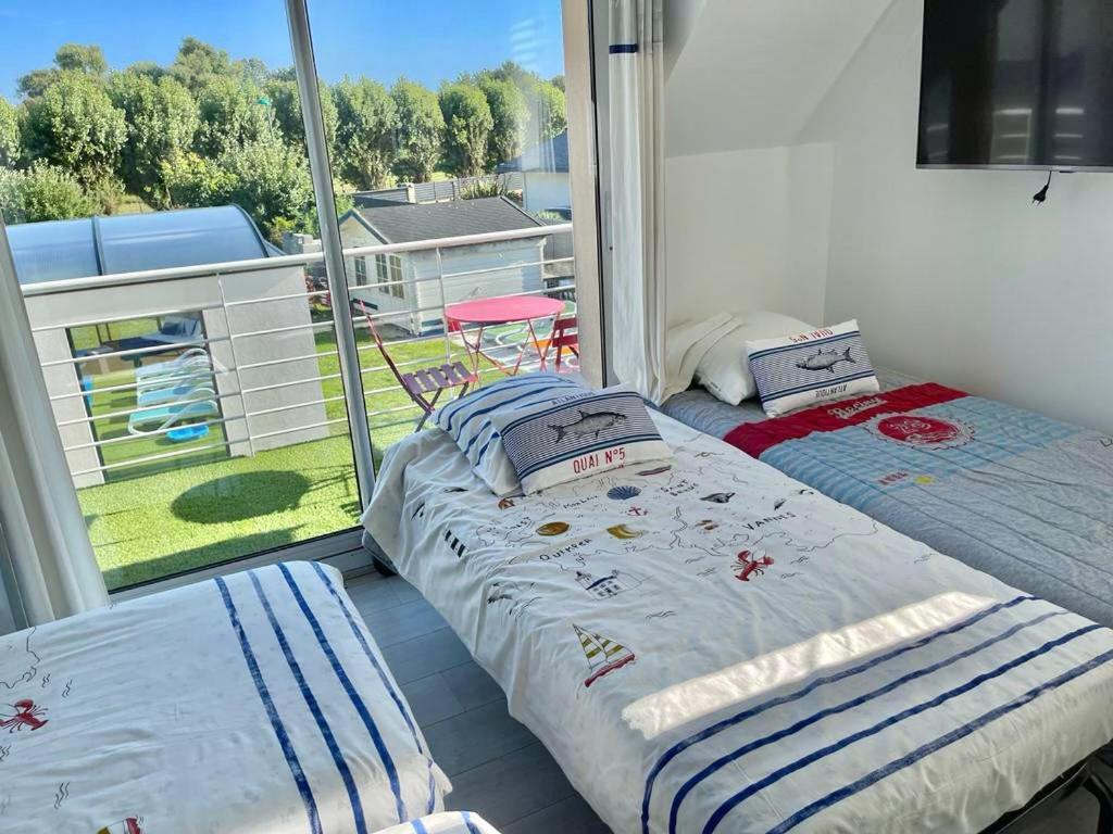 2 Betten in einem Zimmer mit einem großen Fenster in der Unterkunft La Villa KEROMER in Étel