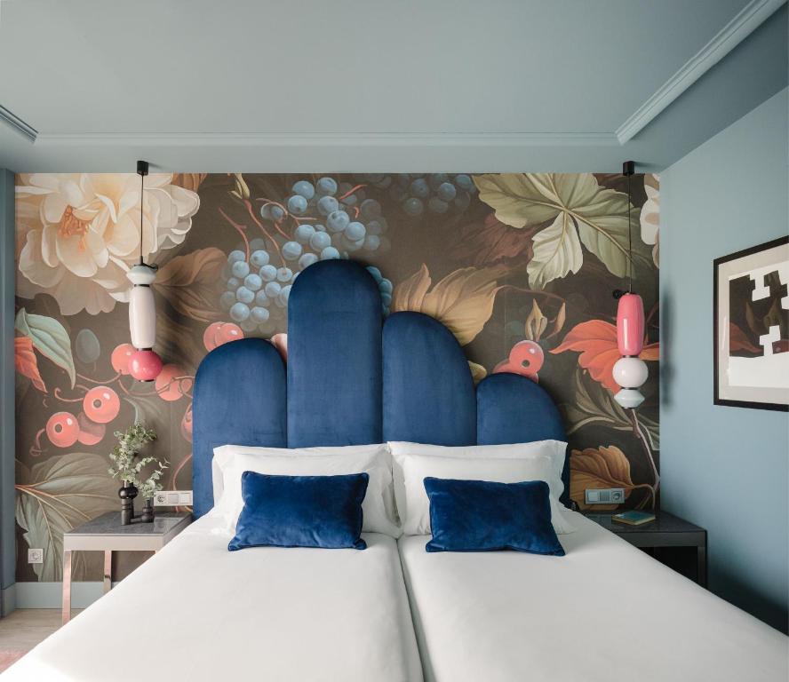 a bedroom with a large bed with a floral wall at Hotel Antik San Sebastián in Donostia-San Sebastián