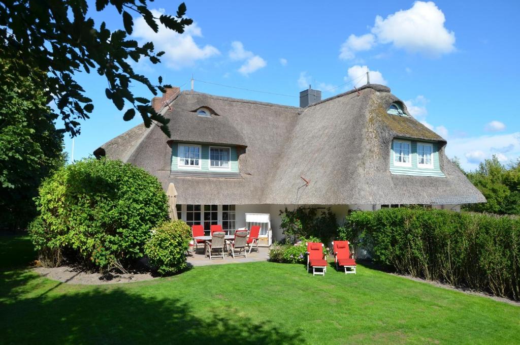 a house with a thatched roof with red chairs at Litzkow 16101 in Archsum