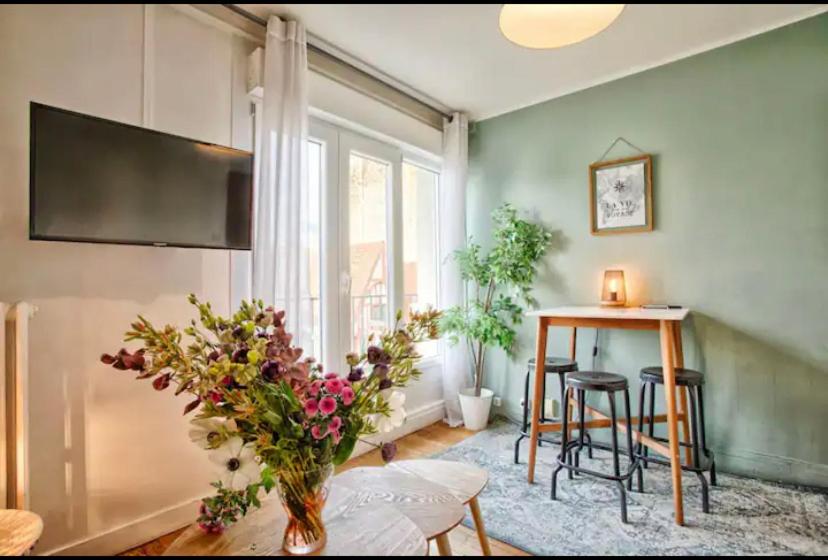 - un salon avec une table et un vase de fleurs dans l'établissement Charmant deux pièces Caen centre, à Caen