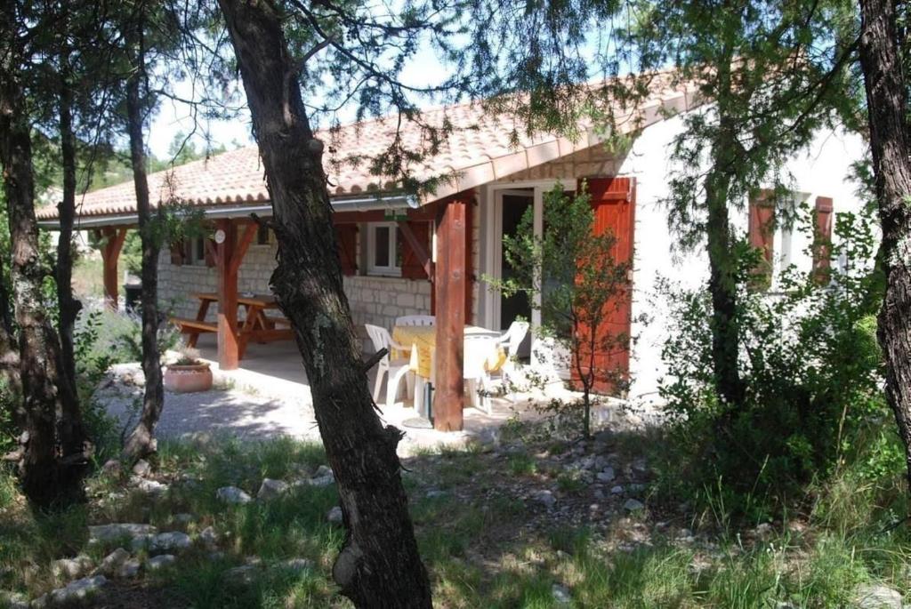 a small white house with a picnic table in a yard at La Chélidoine in Labeaume