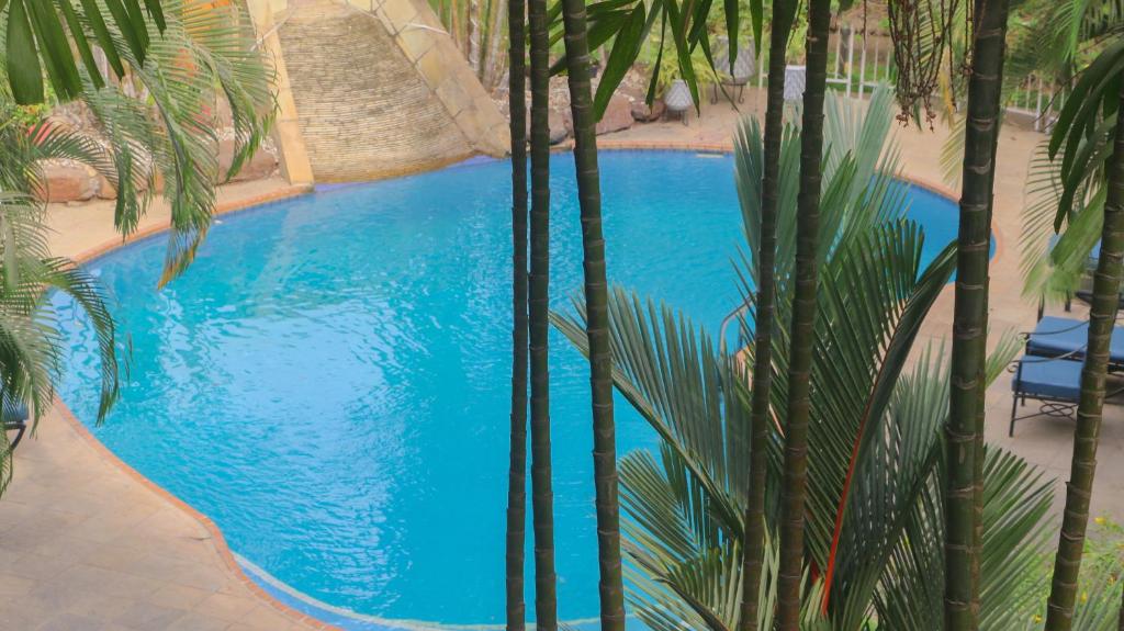 an overhead view of a blue swimming pool with palm trees at Palm Court in Accra