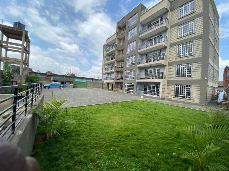 a large apartment building with a green lawn in front of it at Riiri Heights Ong'ata Rongai in Ongata Rongai 