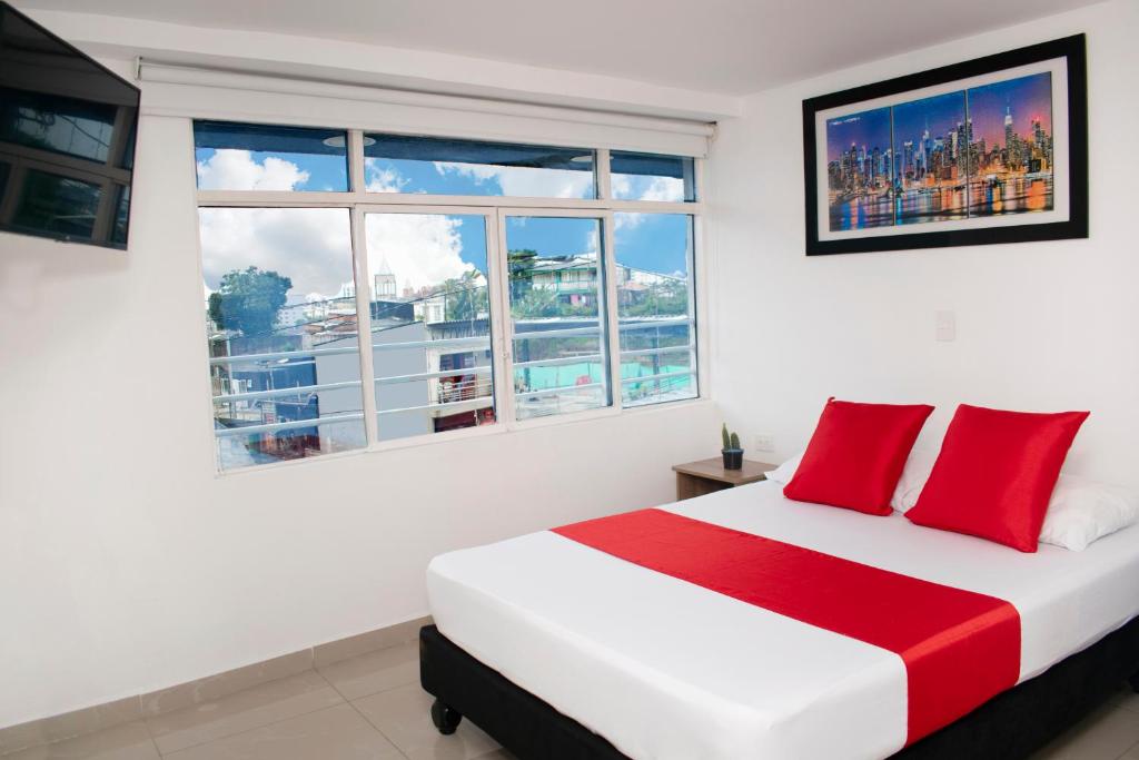 Schlafzimmer mit einem Bett mit roten Kissen und einem Fenster in der Unterkunft Hotel Los Angeles in Calarcá