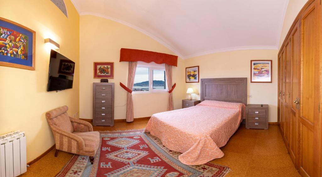sypialnia z łóżkiem, krzesłem i oknem w obiekcie Casa Vila do mar w mieście Baiona