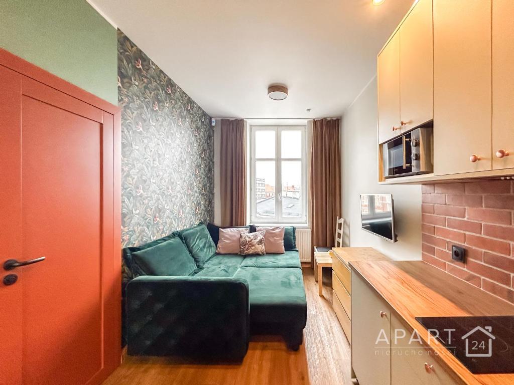 uma sala de estar com um sofá verde numa cozinha em Biskupia Central Apartment em Gdansk