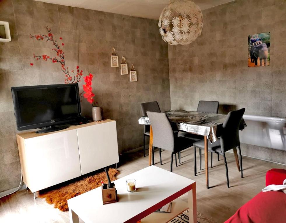 salon z telewizorem, stołem i krzesłami w obiekcie La maison au pays de la nature ,6 couchages w mieście Breginj