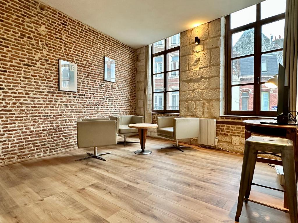 een wachtkamer met stoelen en een bakstenen muur bij Le Nid de Saint André in Lille