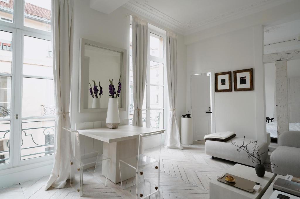 - un salon blanc avec un vase de fleurs sur une table dans l'établissement Opalin, à Paris