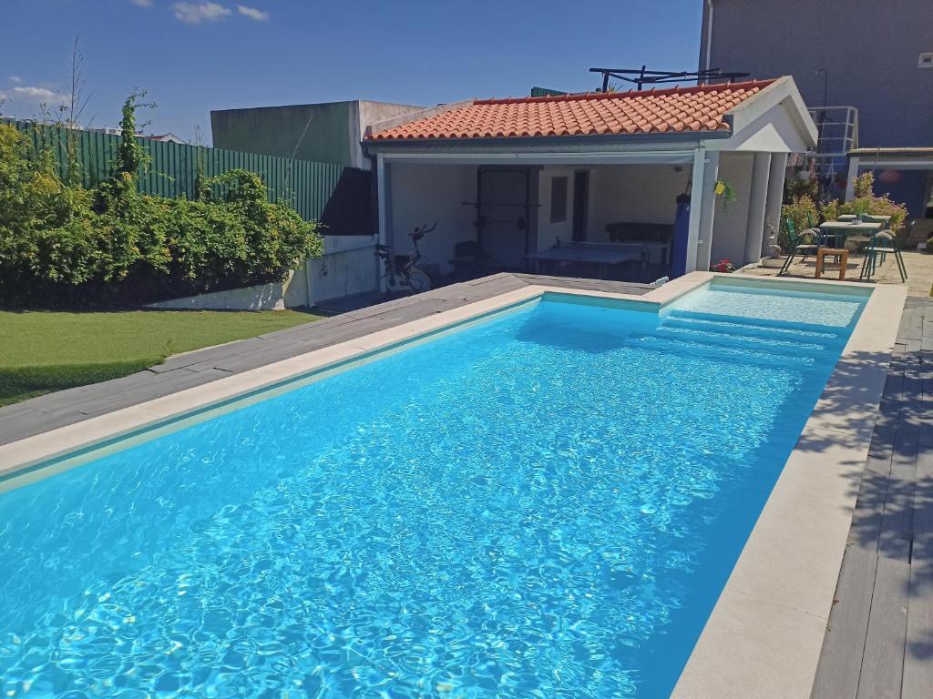 a swimming pool with blue water in front of a house at Mata Beach Caparica in Costa da Caparica