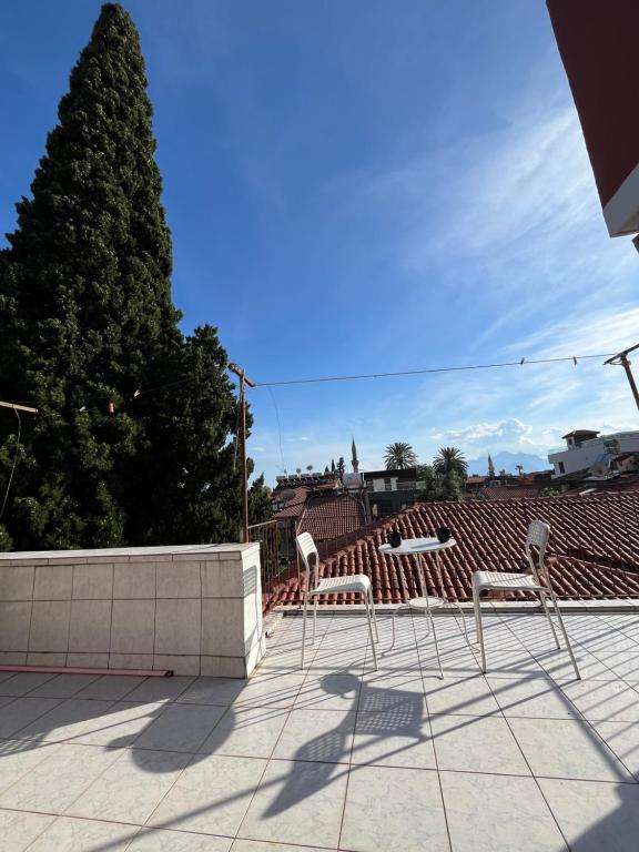 eine Gruppe von Stühlen auf einer Terrasse mit einem Baum in der Unterkunft Erkal Pension in Antalya