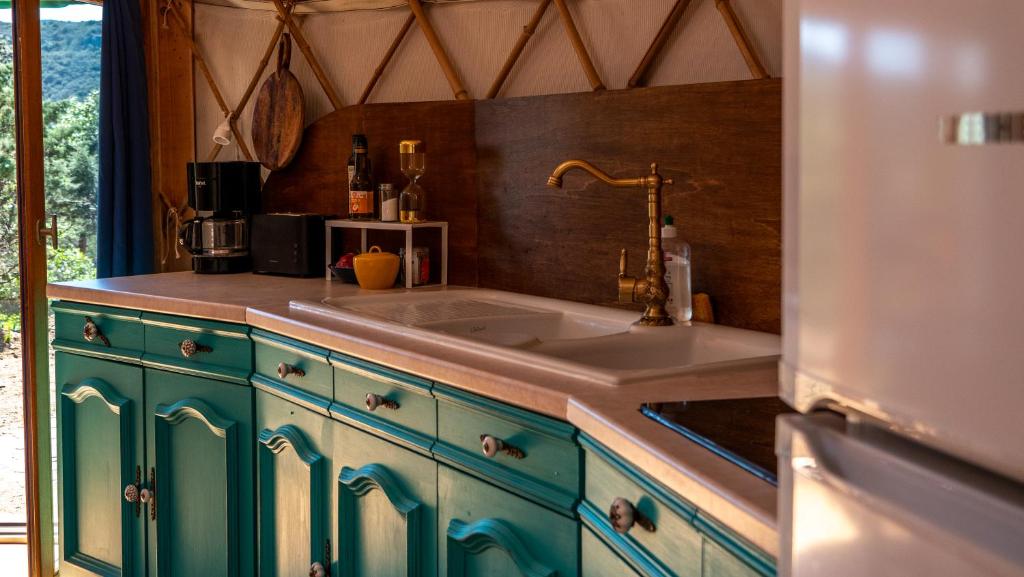 une cuisine avec des armoires bleues et un évier dans l'établissement Les Cabanes d'ErbeFol, à Ansignan