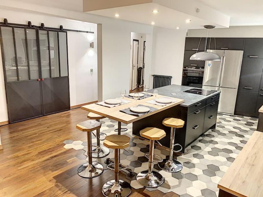 - une cuisine avec une table et quelques tabourets de bar dans l'établissement Appartement type industriel centre ville, à Vannes