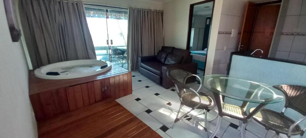 uma sala de estar com uma mesa de vidro e uma banheira em Hotel Arrecife dos Corais em Cabo de Santo Agostinho