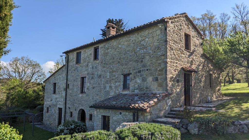 een oud stenen gebouw in een veld met bomen bij Borgo Fastelli in Sarteano