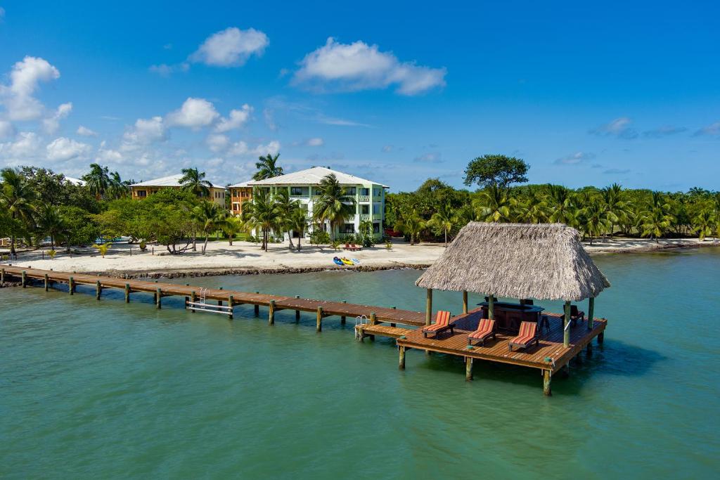 a pier with chairs and a resort on the water at The Villas at Cocoplum in Placencia