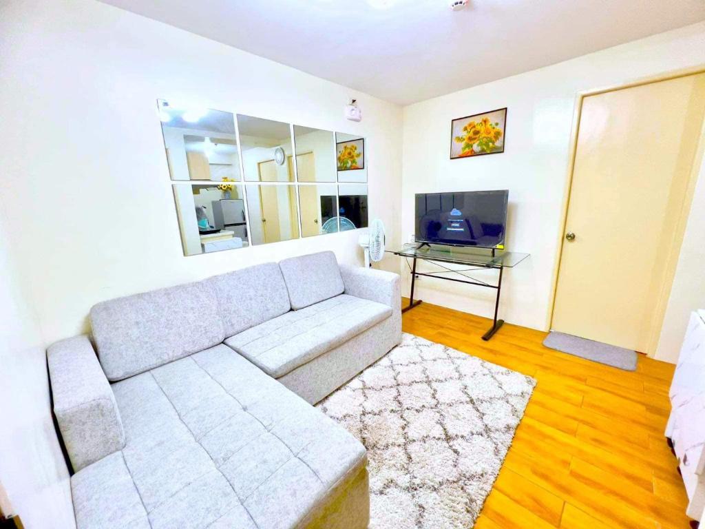 a living room with a white couch and a television at SEAWIND CONDO Davao City in Davao City