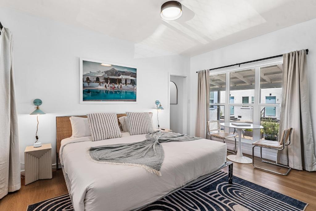 ein weißes Schlafzimmer mit einem großen Bett und einem Tisch in der Unterkunft Aliza Hotel in Los Angeles