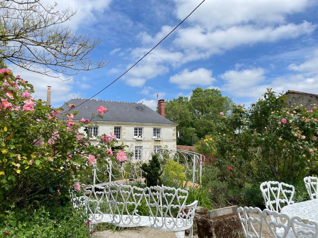 Nueil-sur-LayonにあるChambre de charme dans un jardin de 1500m2の白い椅子が置かれた白い家
