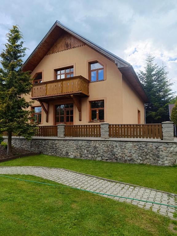 a house with a balcony and a stone wall at Privát Majo - Váš oddych na Liptove in Liptovský Mikuláš