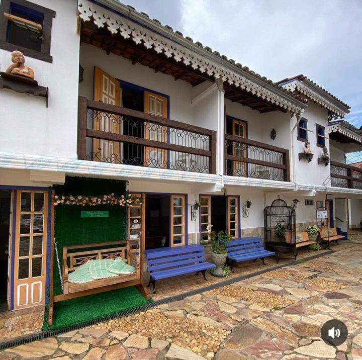 um edifício com bancos azuis à sua frente em Pouso das Gerais em Tiradentes