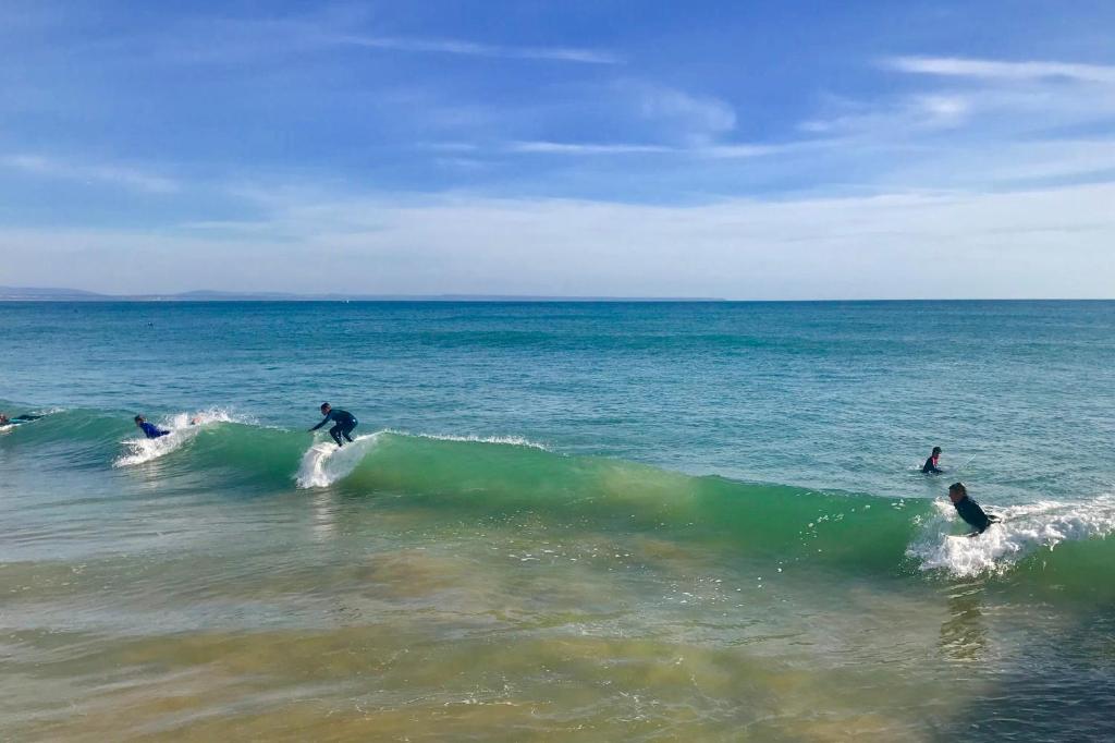a group of people riding a wave in the ocean at Atlantic Waves Accommodation in Carcavelos