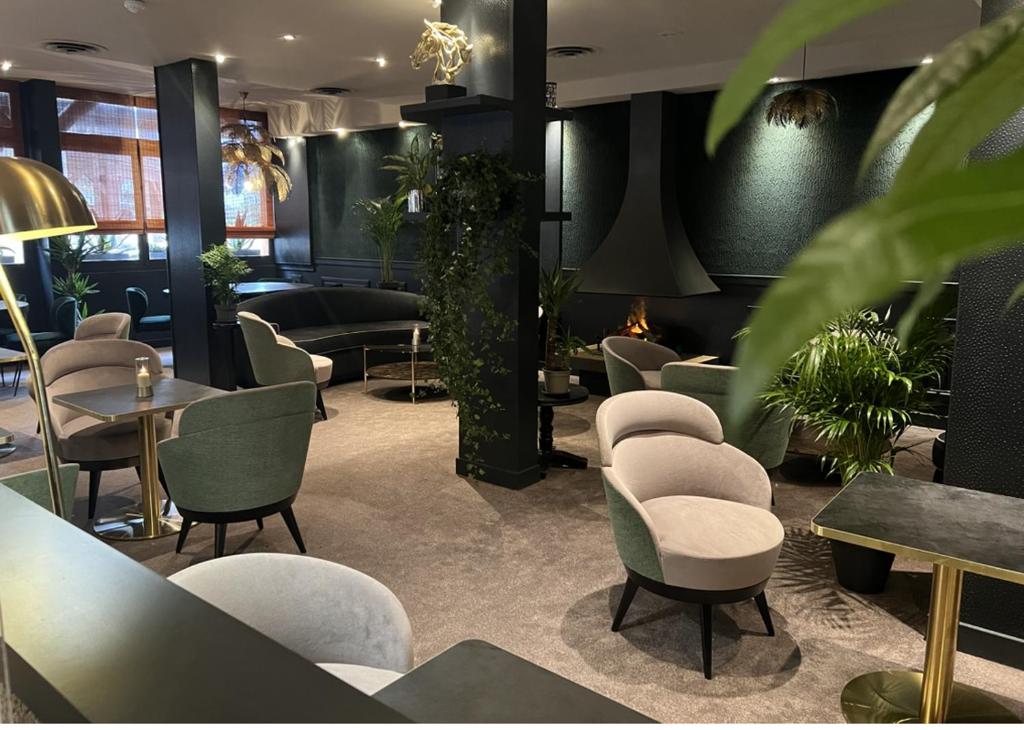 a waiting room with chairs and tables and plants at Le Trophée Boutique Hôtel Spa- La Loggia Appart'hôtel in Deauville