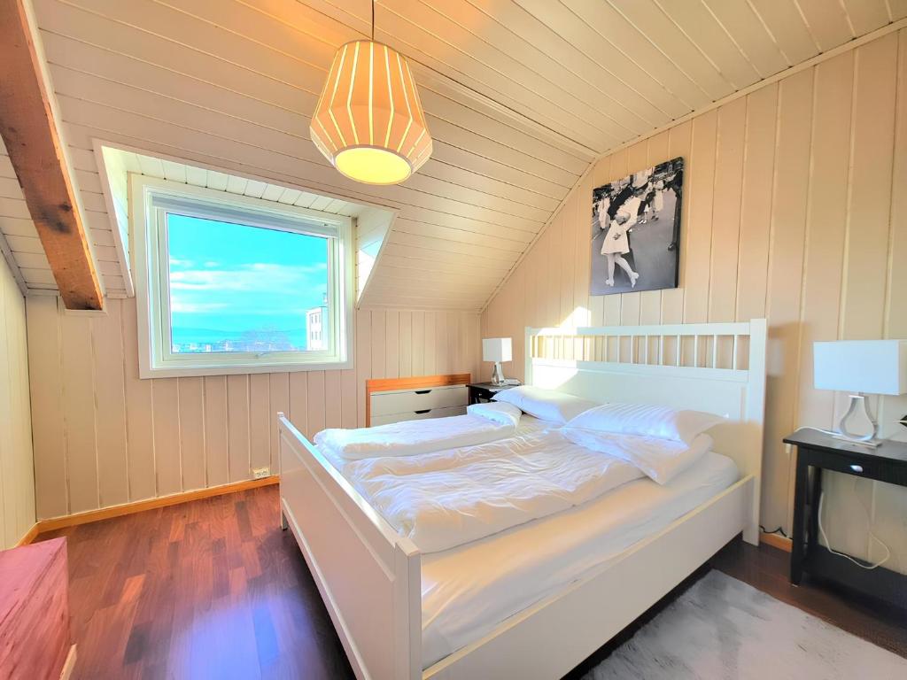 トロンハイムにあるSunset Penthouse, Fjord View & Parkingのベッドルーム(白いベッド1台、窓付)
