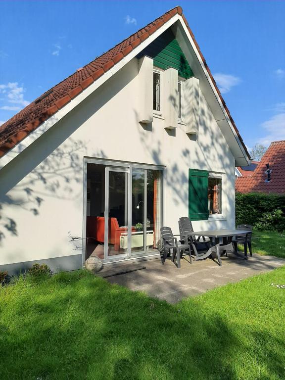 a white house with a patio with two chairs at libelle in Sint Nicolaasga