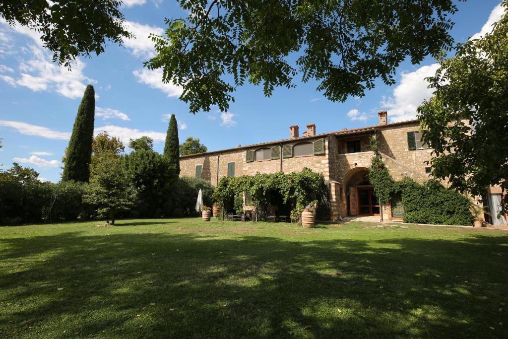 uma antiga casa de pedra com um grande quintal em Residenza Santa Maria In Borraccia em Magliano in Toscana