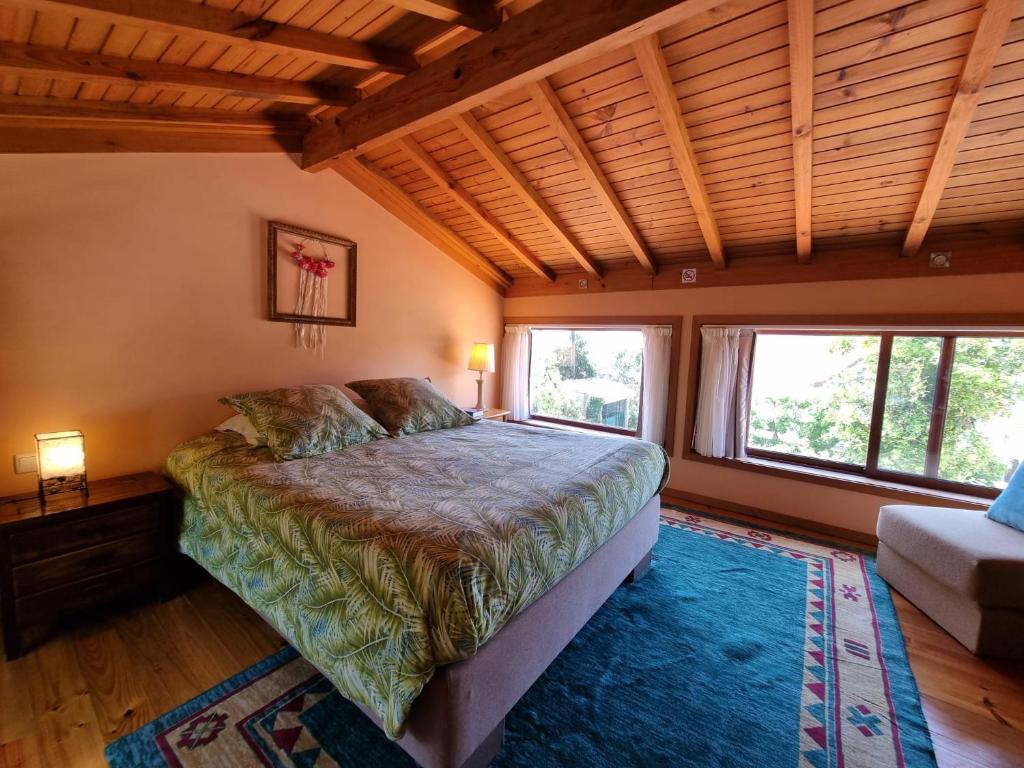 um quarto com uma cama e duas janelas em Alpendre em Guimarães