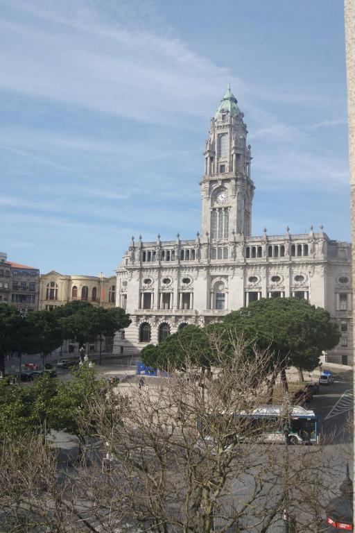 ein großes weißes Gebäude mit einem Uhrturm in der Unterkunft Hotel Chique Aliados in Porto