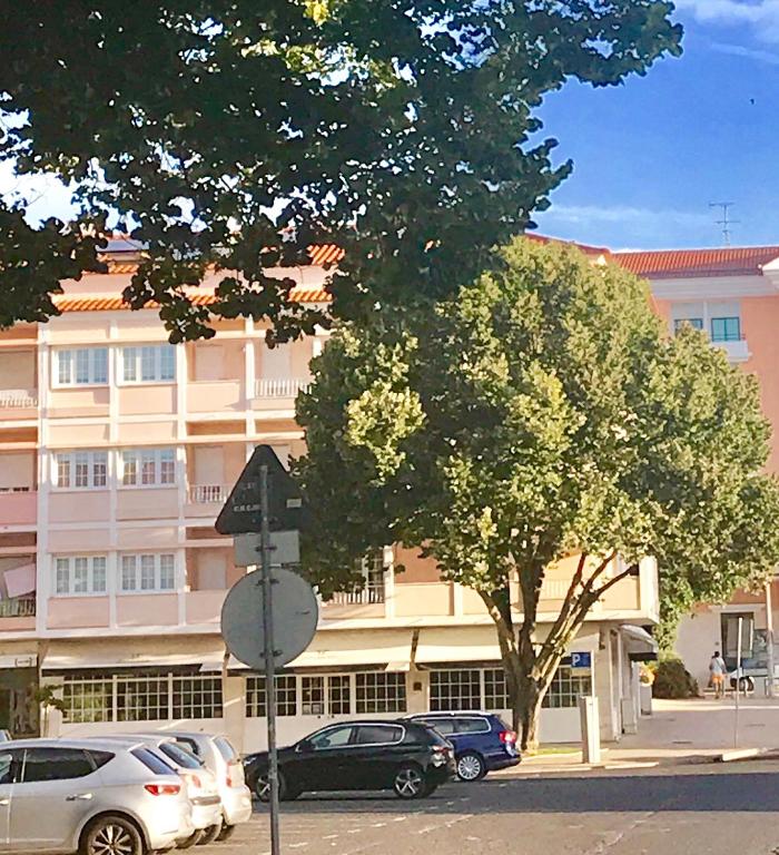 a tree in front of a building with parked cars at Atlantic Waves Accommodation in Carcavelos