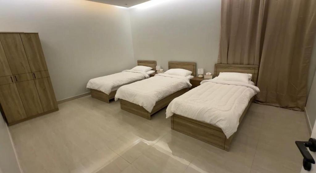 Hotel Apartment - 12 - LAvner Al Moteab في الرياض: غرفة بثلاث أسرة مع أغطية بيضاء وستائر