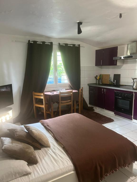 a bedroom with a bed and a kitchen with a table at Studio privatif in Goussainville
