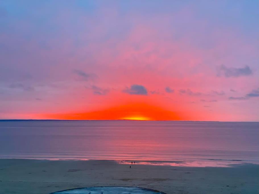 - un coucher de soleil sur la plage au loin dans l'établissement L'appart du Val, Vue mer, à Pléneuf-Val-André