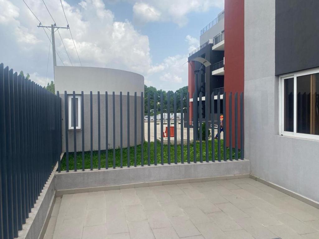 einen Zaun vor einem Gebäude neben einem Gebäude in der Unterkunft Golf Mews Inspired Living in Benin City