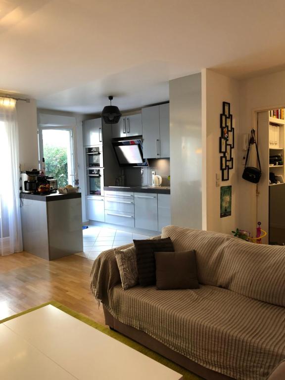un salon avec un canapé et une cuisine dans l'établissement Idéal T3 top confort Massy Atlantis, à Massy