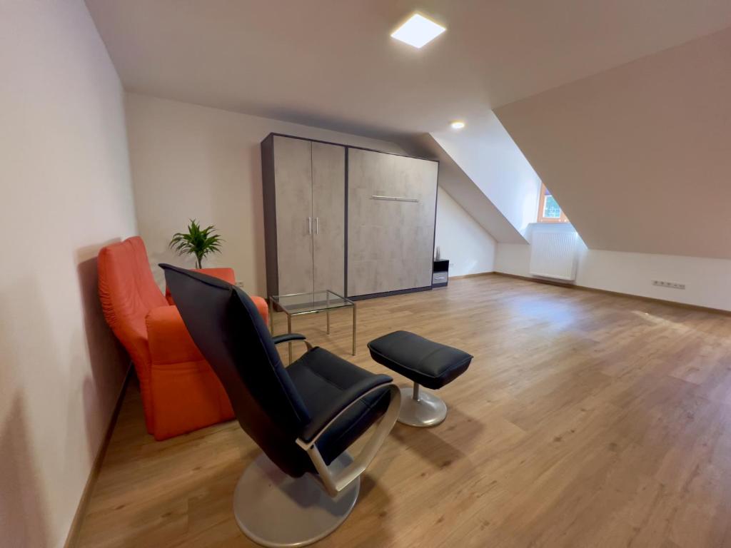 ein Wohnzimmer mit einem Sessel und einem orangefarbenen Sofa in der Unterkunft Ferienwohnungen zur POST 2 in Breitenbrunn