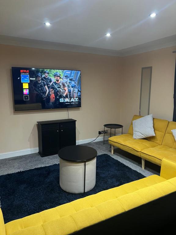 sala de estar con sofá amarillo y TV de pantalla plana en Modern 3 Bed House for 6 guests en Nevendon