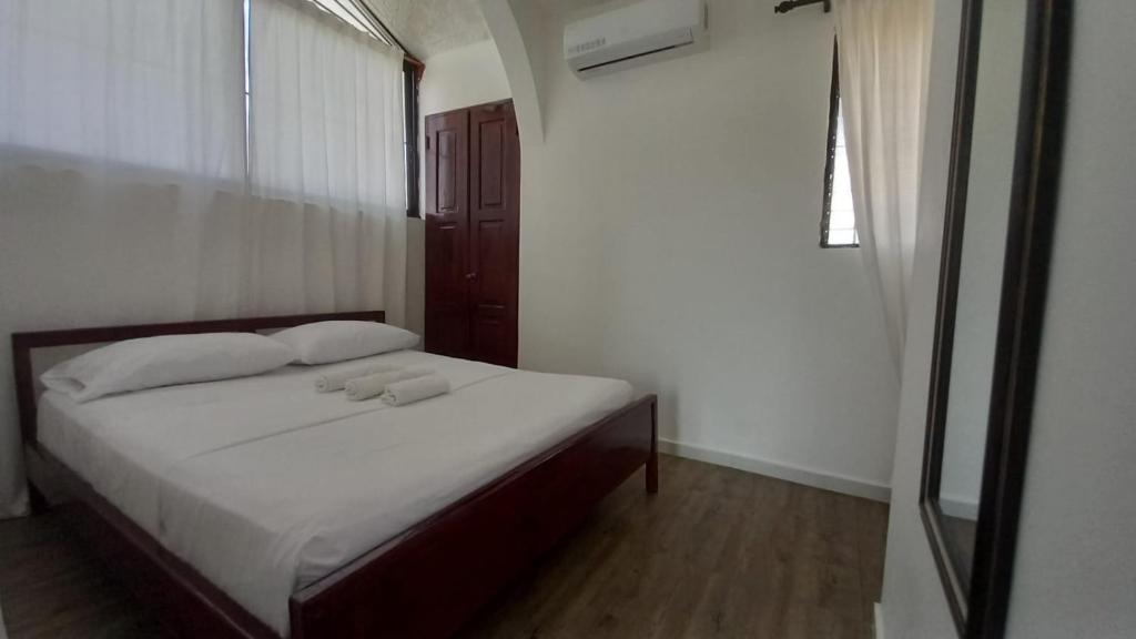 a bedroom with a bed with white sheets and a window at Coral Village Toby in Santa Bárbara de Samaná