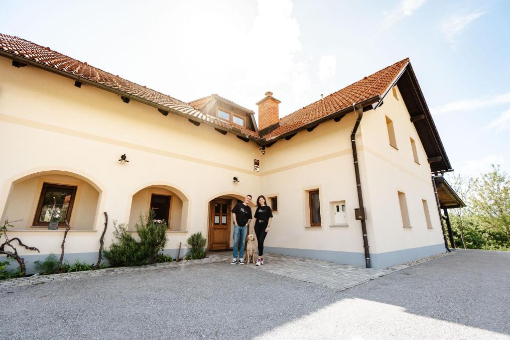2 personnes debout devant un bâtiment dans l'établissement Zelena Oaza - B&B, à Miklavž pri Ormožu