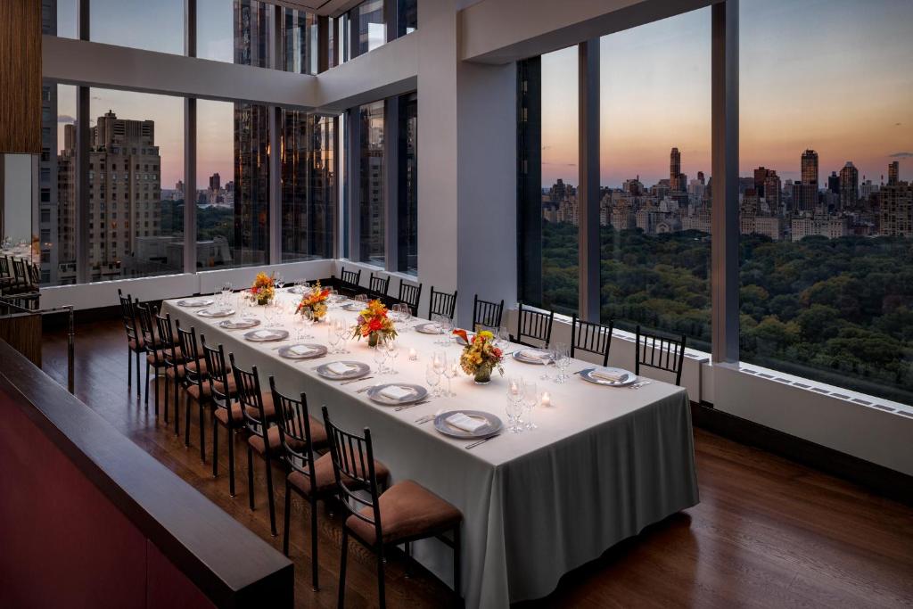 a long dining table in a room with large windows at Mandarin Oriental, New York in New York
