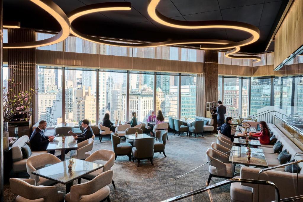people sitting at tables in a restaurant with large windows at Mandarin Oriental, New York in New York