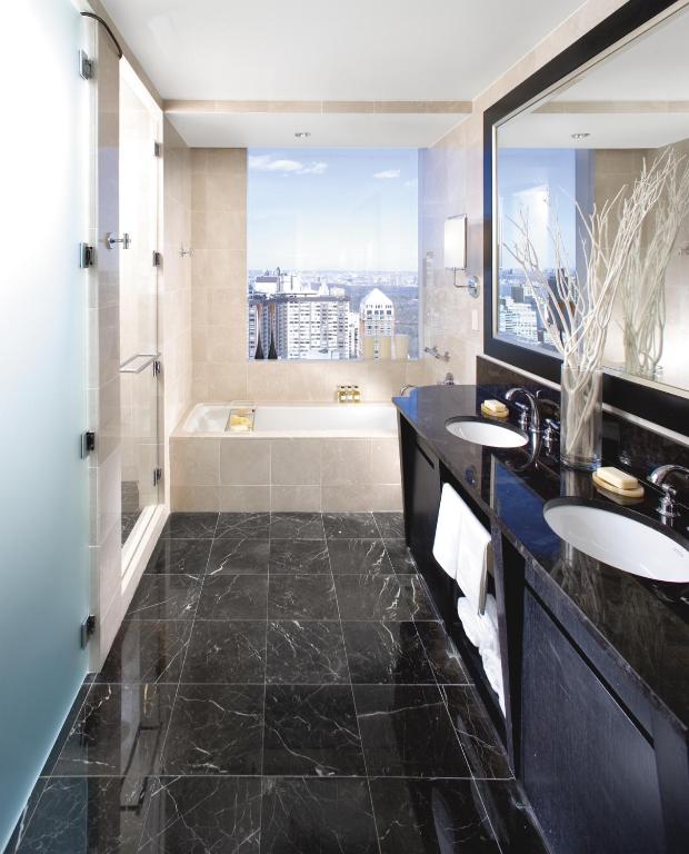 a bathroom with two sinks and a tub with a window at Mandarin Oriental, New York in New York